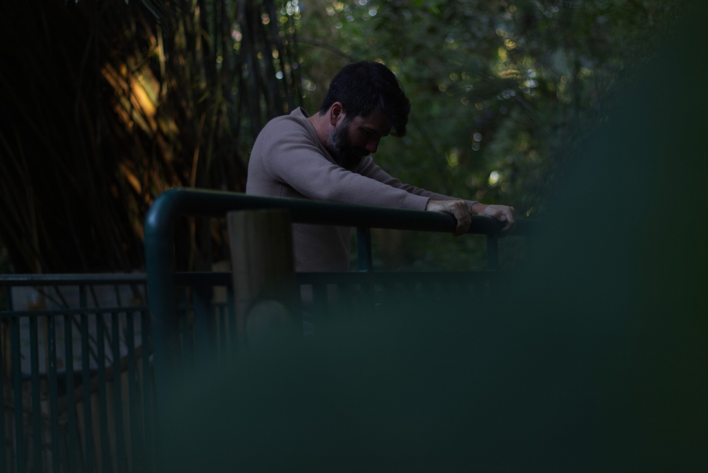 Victor Luna leaning on a railing in a garden